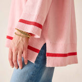 Pink sweater with red stripes worn by a person, with a focus on the sleeve and hand.