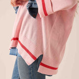 Pink and red knit v-neck sweater with bold horizontal stripes and relaxed fit.
