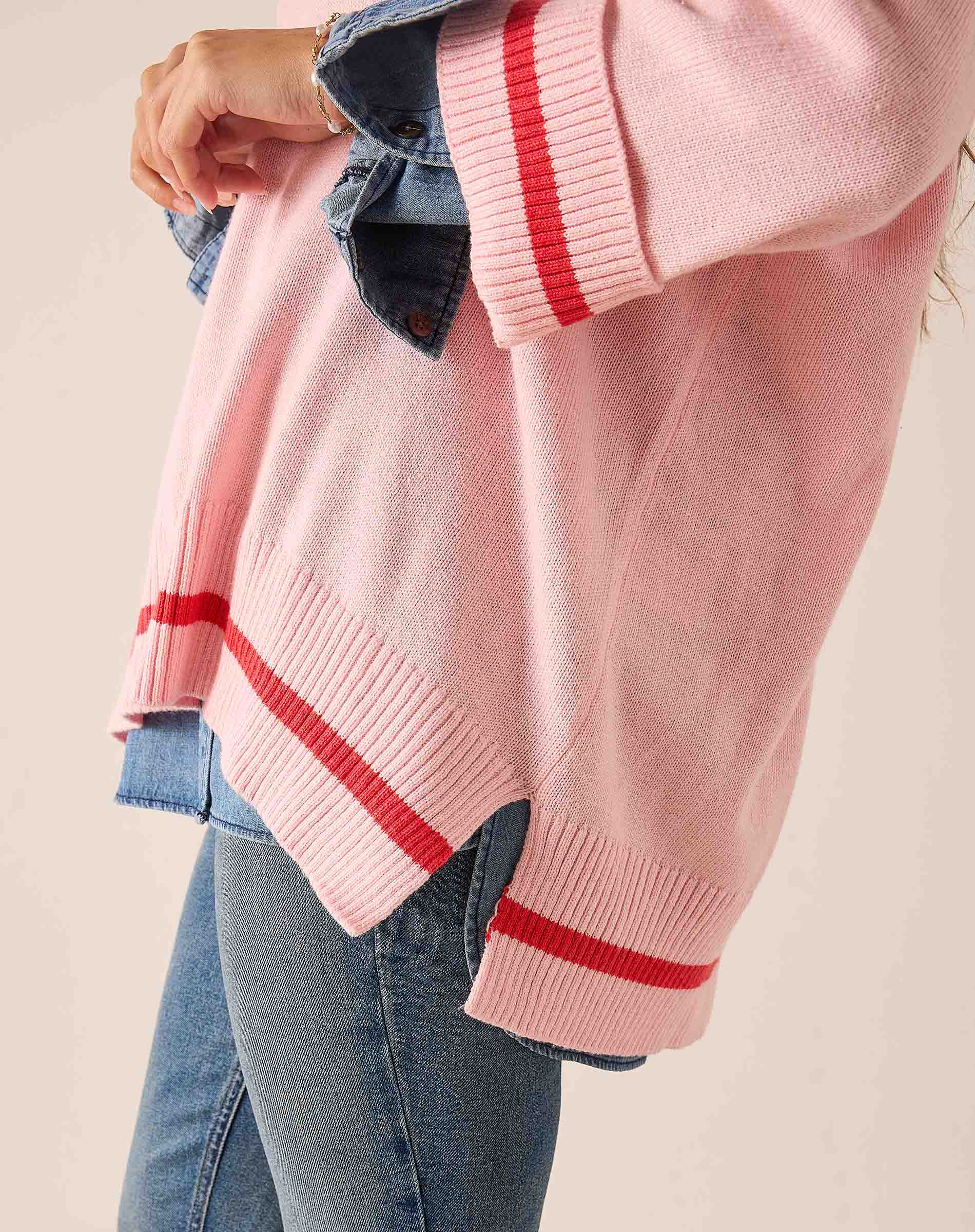 Pink and red knit v-neck sweater with bold horizontal stripes and relaxed fit.
