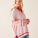 Woman wearing a pink sweater with red trim on a plain background