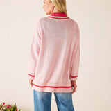 Woman wearing a pink sweater with red trim against a beige background