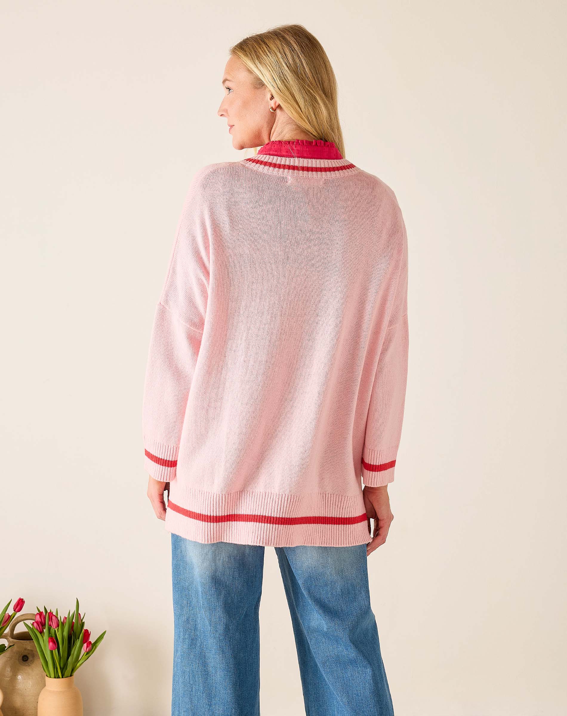 Woman wearing a pink sweater with red trim against a beige background