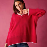 Raspberry pink v-neck knit top with ribbed details and white trim over a collared shirt.