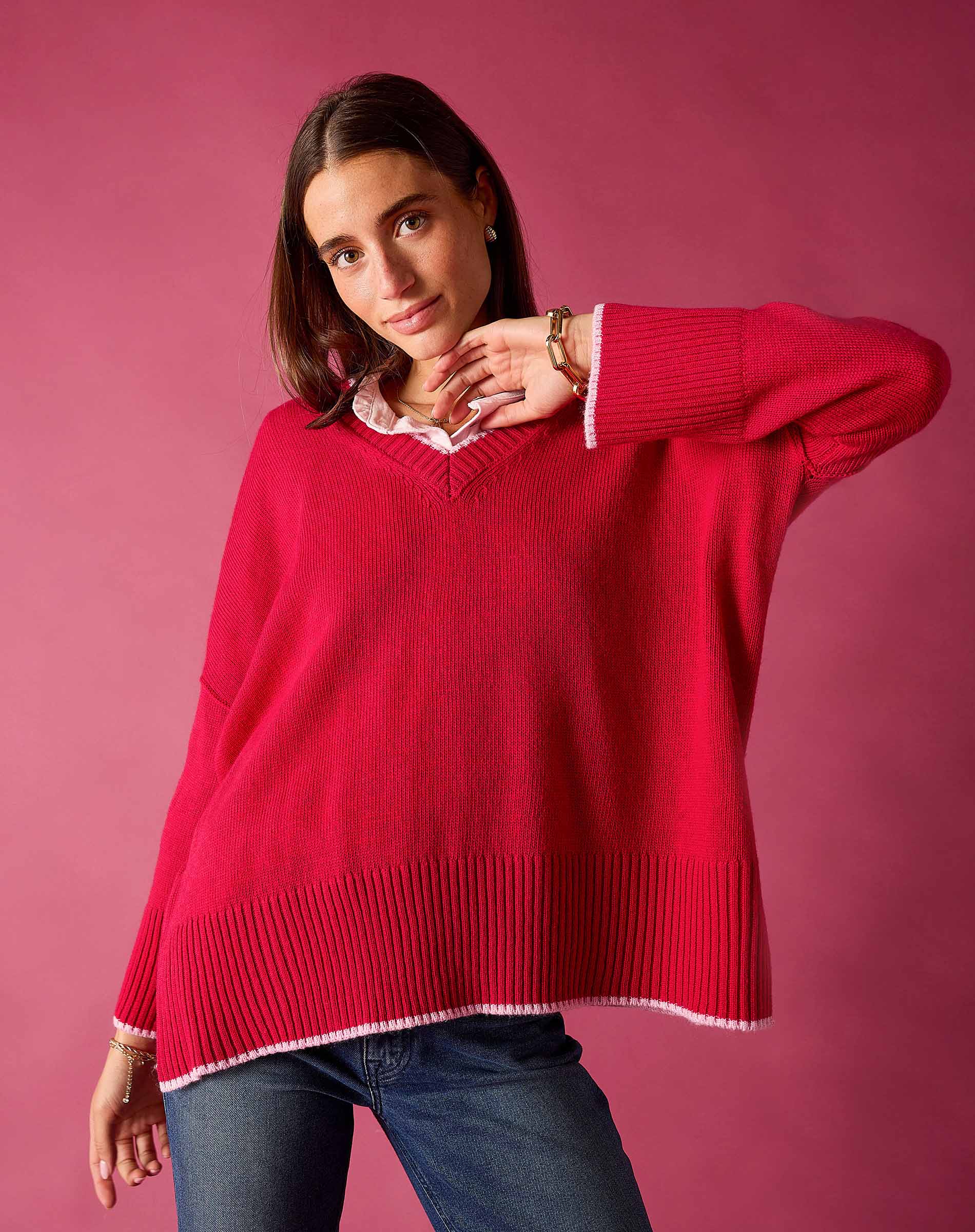 Raspberry pink v-neck knit top with ribbed details and white trim over a collared shirt.