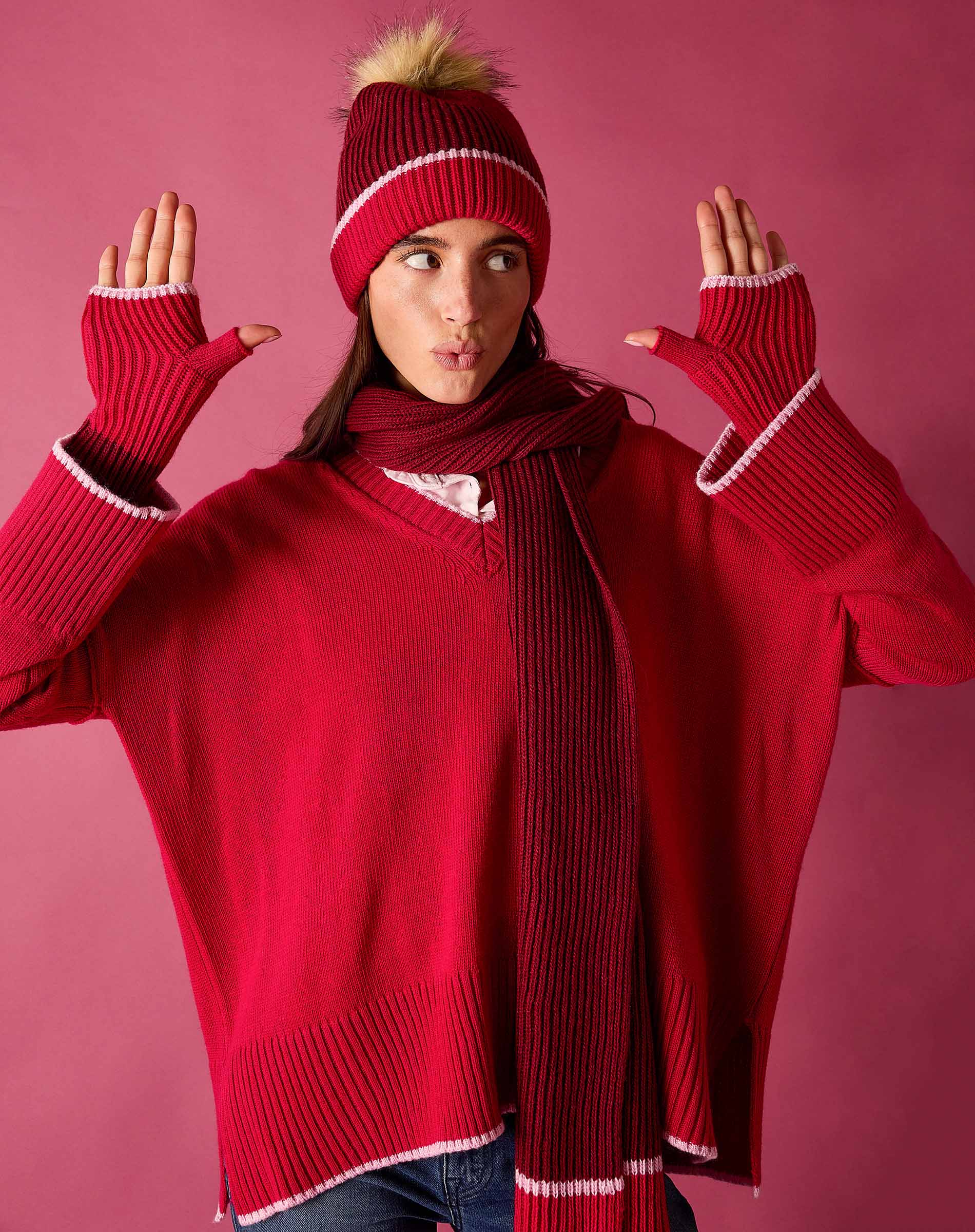 Raspberry pink v-neck knit sweater with white trim and a matching pom-pom beanie.