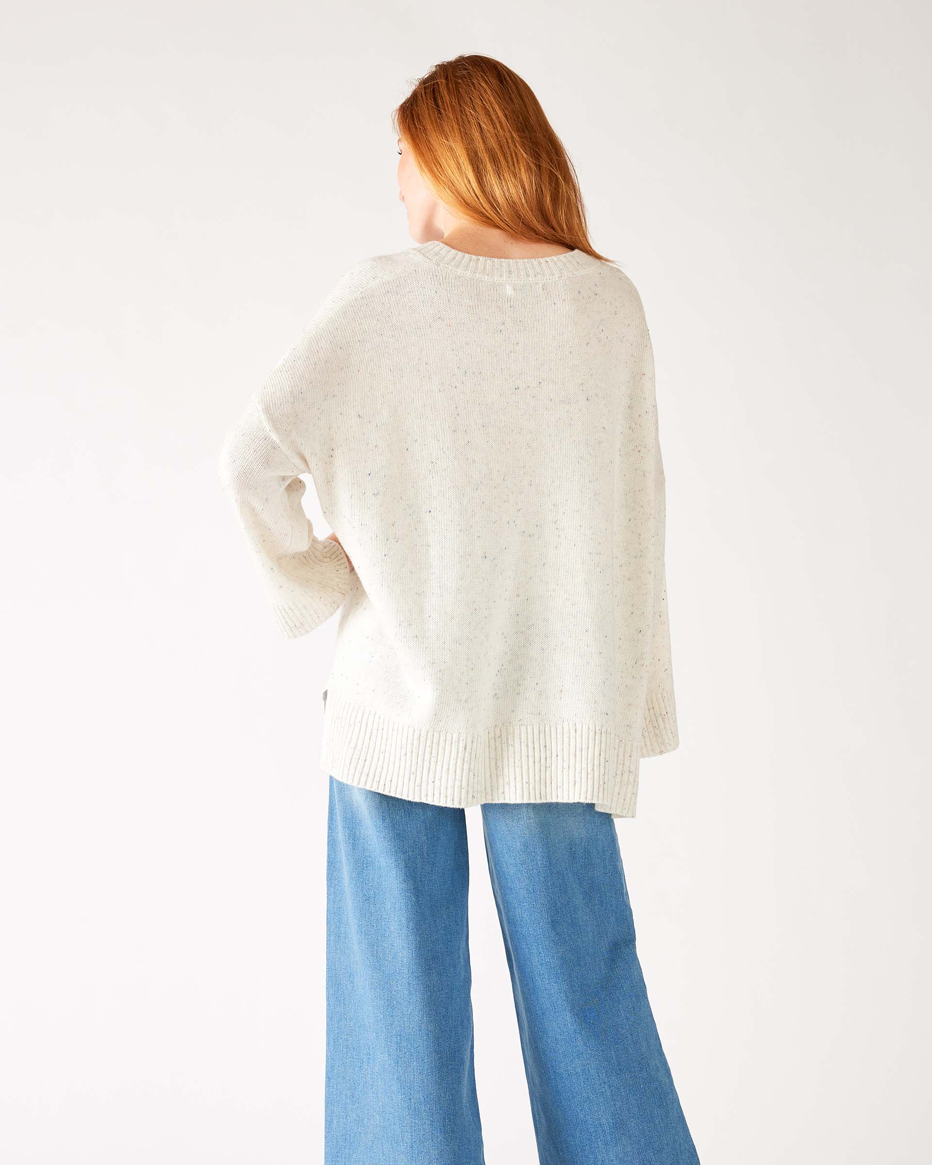 rearview of woman wearing mersea montauk v-neck sweater with wide sleeves in cream color