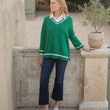 Woman wearing a green sweater with white trim in an outdoor setting.