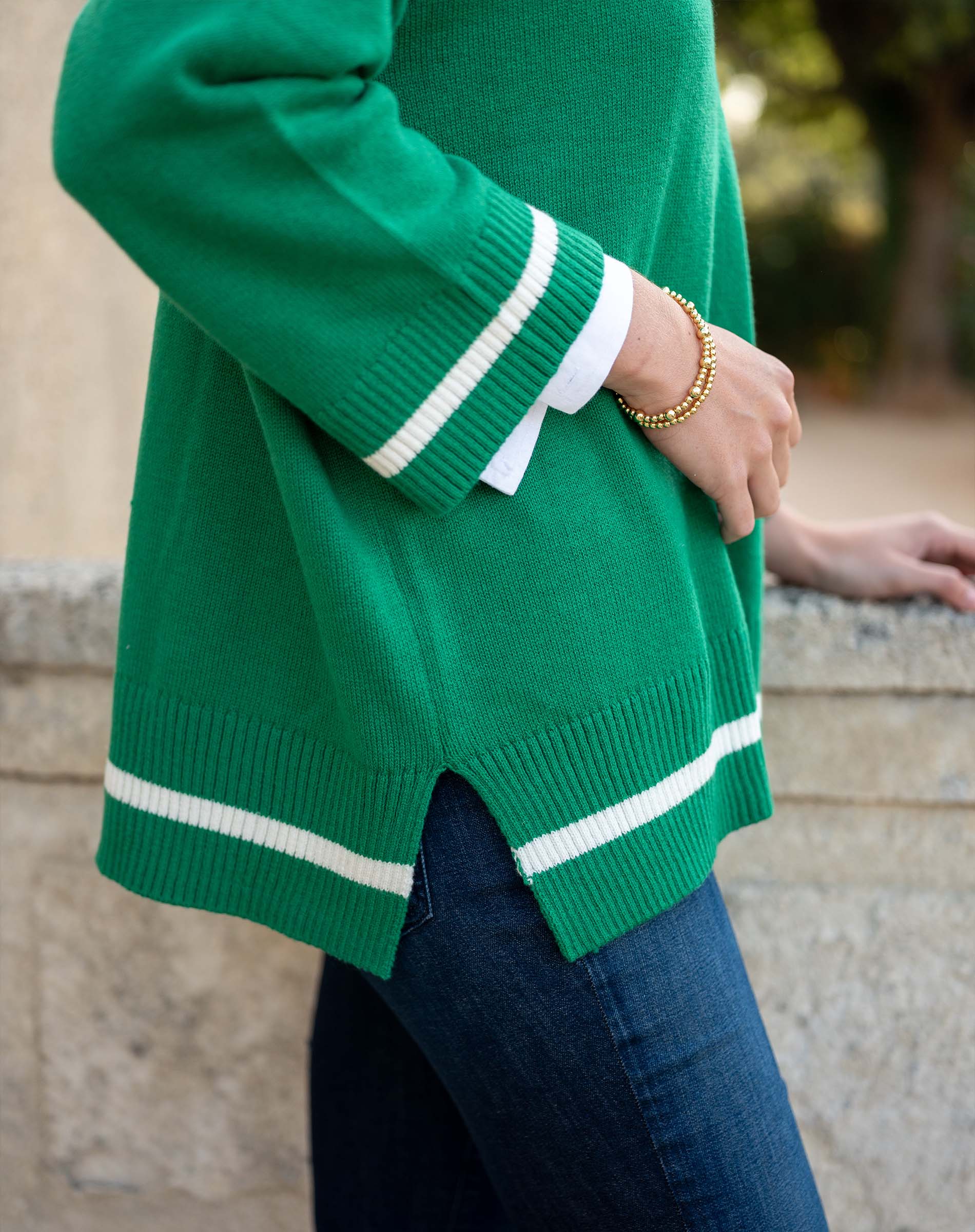 Green sweater with white stripes worn by a person, blurred background