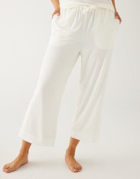 female wearing beige pajama pants on a white background