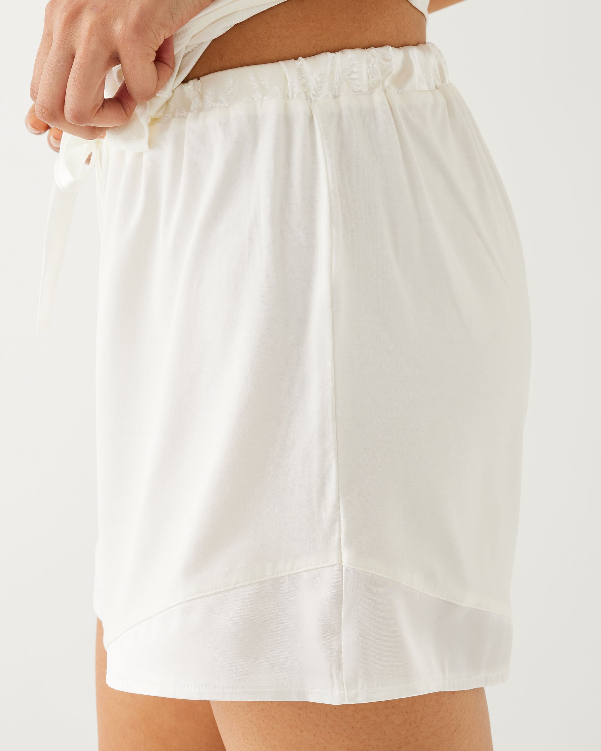 female wearing white pajama shorts and matching top on a white background