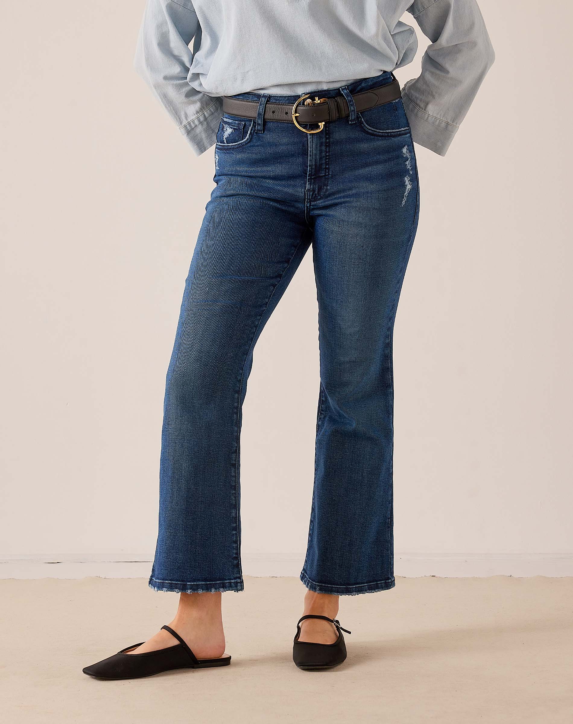 Medium-wash blue denim flare jeans with frayed hems and a vintage-inspired distressed look.