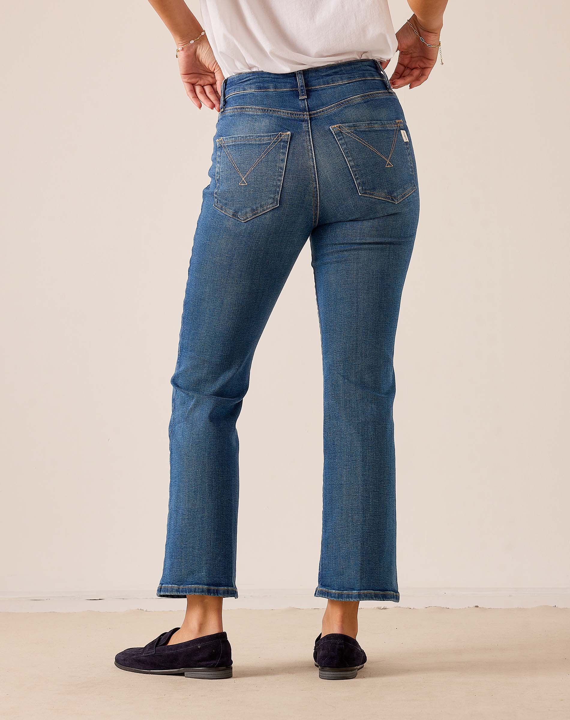Blue-wash denim-style relaxed fit flared-leg pants with stitched back pocket details.