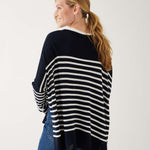 female wearing navy and white striped sweater with blue jeans backward on a white background