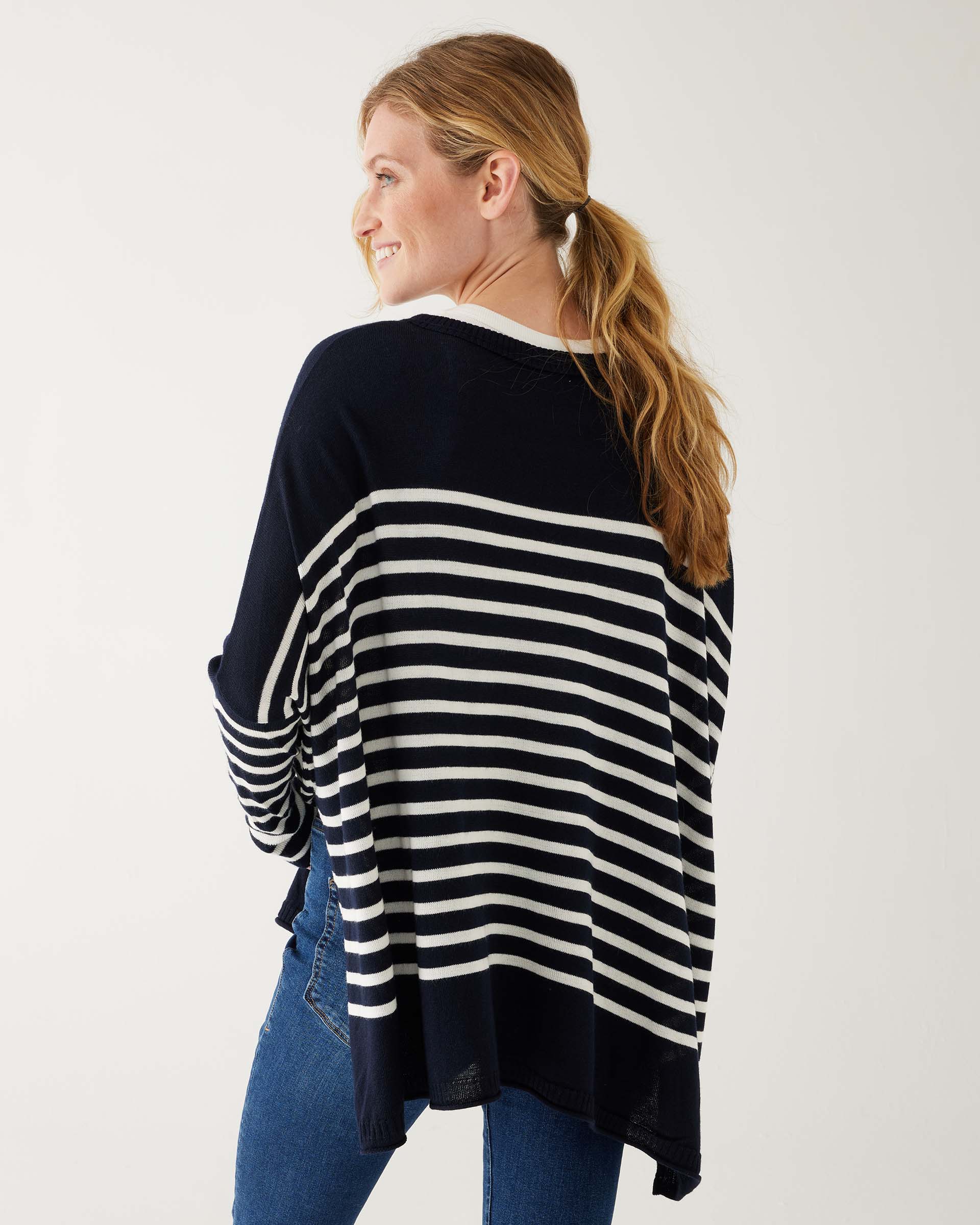 female wearing navy and white striped sweater with blue jeans backward on a white background