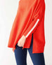 closeup of sleeve on woman wearing mersea newport sweater in chili red with white accent stripe on lower sleeve , a split front turtleneck and ribbed sleeves.