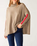 woman wearing mersea newport sweater in driftwood brown with red accent stripe down lower sleeve with a split front turtleneck and ribbed sleeves