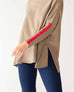 closeup of sleeve on woman wearing mersea newport sweater in driftwood brown with red accent stripe down lower sleeve with a split front turtleneck and ribbed sleeves