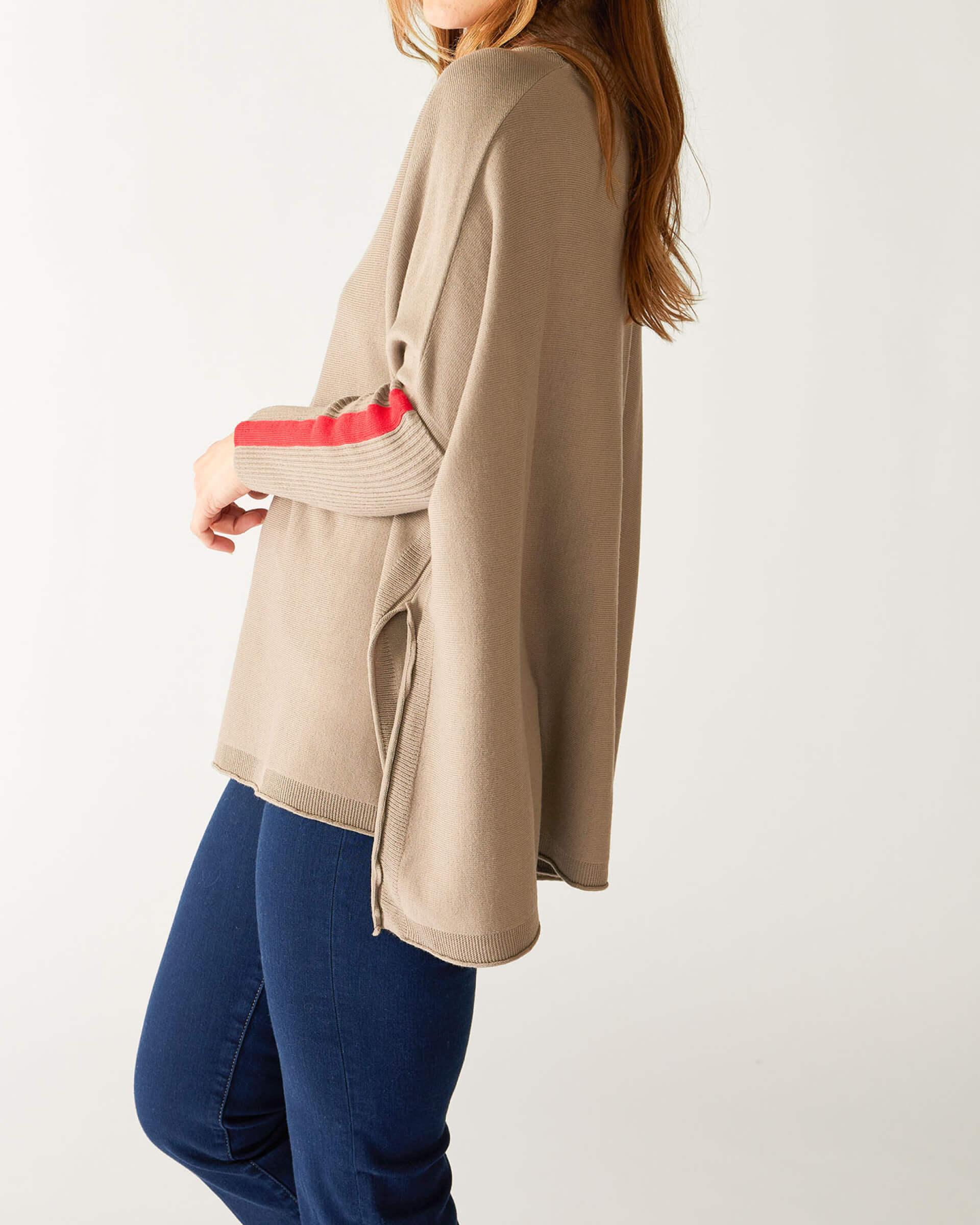 profile of woman wearing mersea newport sweater in driftwood brown with red accent stripe down lower sleeve with a split front turtleneck and ribbed sleeves
