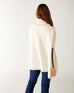 rearview of woman wearing mersea newport sweater in salt storm white with grey accent stripe down lower sleeve with a split front turtleneck and ribbed sleeves
