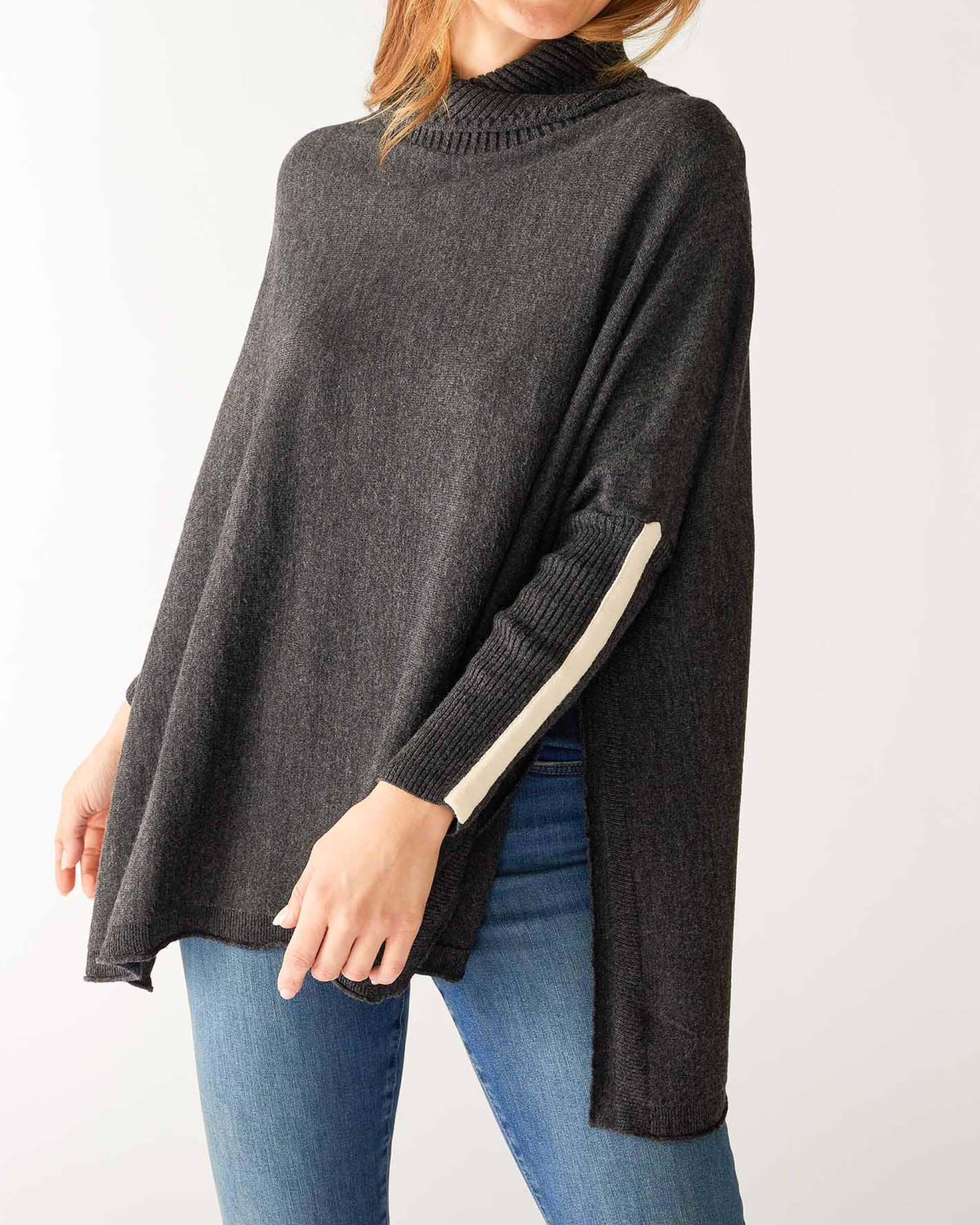 woman wearing mersea newport sweater in storm grey with light salt accent stripe down lower sleeve with a split front turtleneck and ribbed sleeves