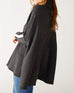 profile of woman wearing mersea newport sweater in storm grey with light salt accent stripe down lower sleeve with a split front turtleneck and ribbed sleeves