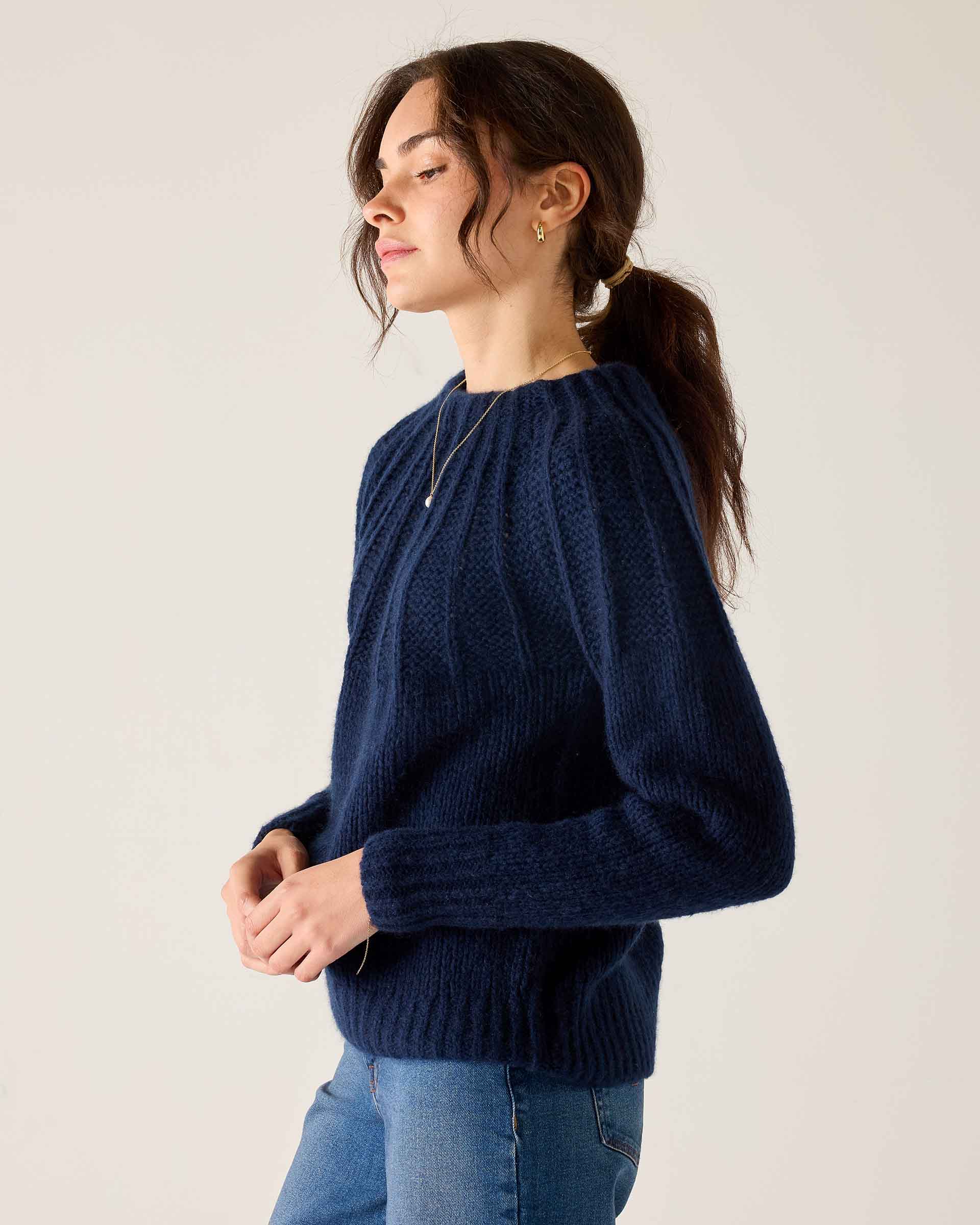 Navy ribbed knit sweater with a rounded neckline and long sleeves.