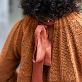 Cinder orange ribbed knit sweater with a large satin ribbon tie.