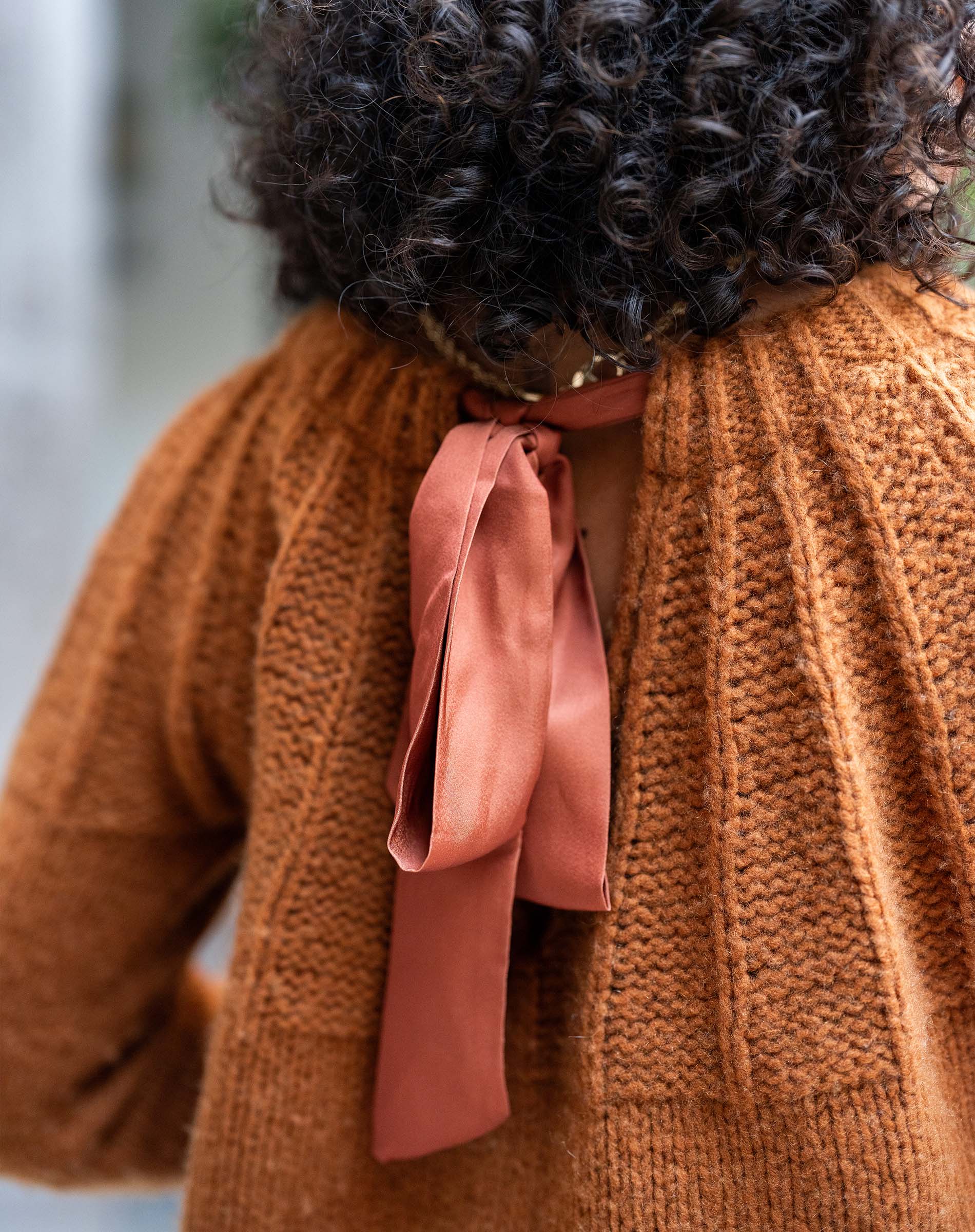 Cinder orange ribbed knit sweater with a large satin ribbon tie.