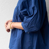 Person wearing a blue blouse with long sleeves against a plain background