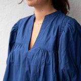 Person wearing a blue dress with a neutral background