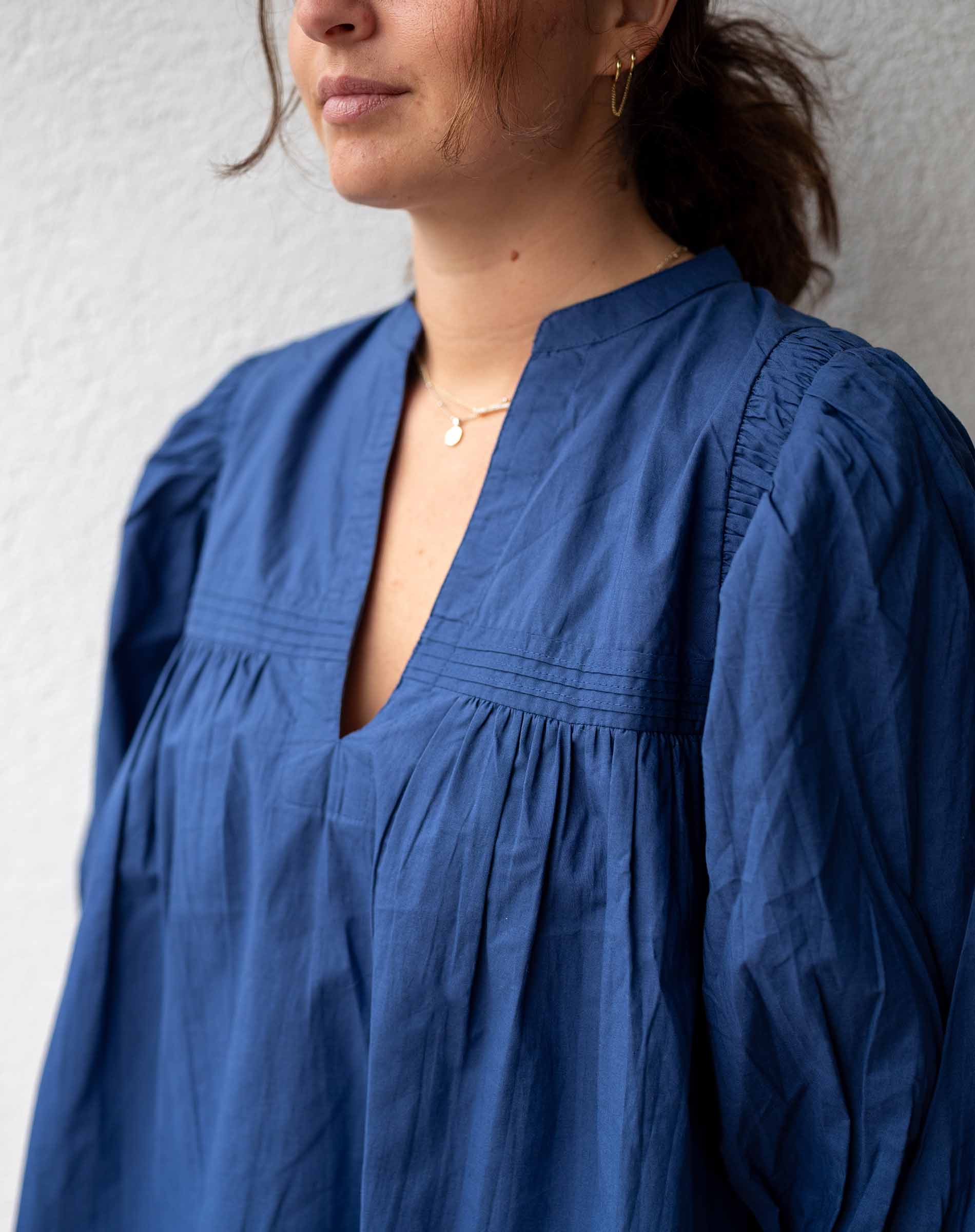 Person wearing a blue dress with a neutral background