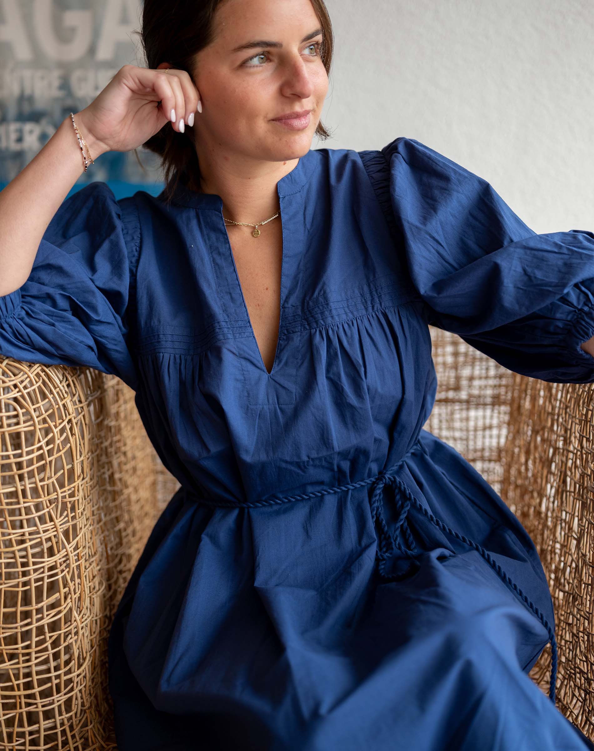 Woman wearing a blue dress sitting on a textured chair.
