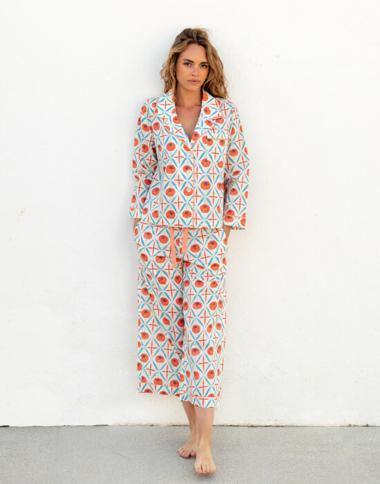 female wearing matching pj set with blue and pink floral print standing in front of a white wall