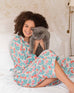 woman on a bed holding a cat wearing over the cotton moon pjs in block print poppy pattern