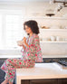 woman sitting on kitchen counter eating cereal wearing over the cotton moon pjs in peony party