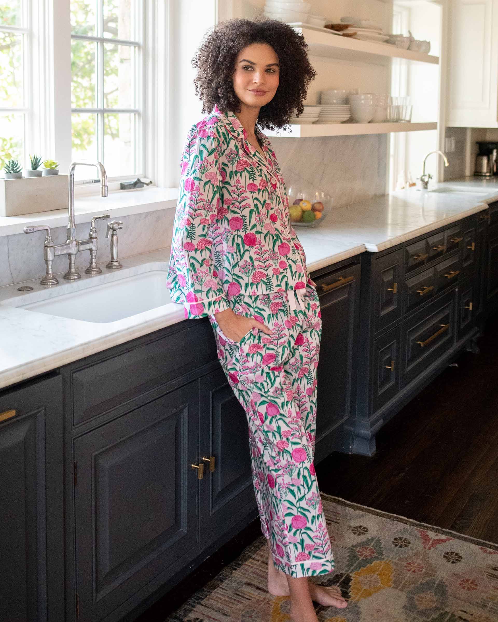 woman in kitchen wearing over the cotton moon pjs in peony party with hands in pockets