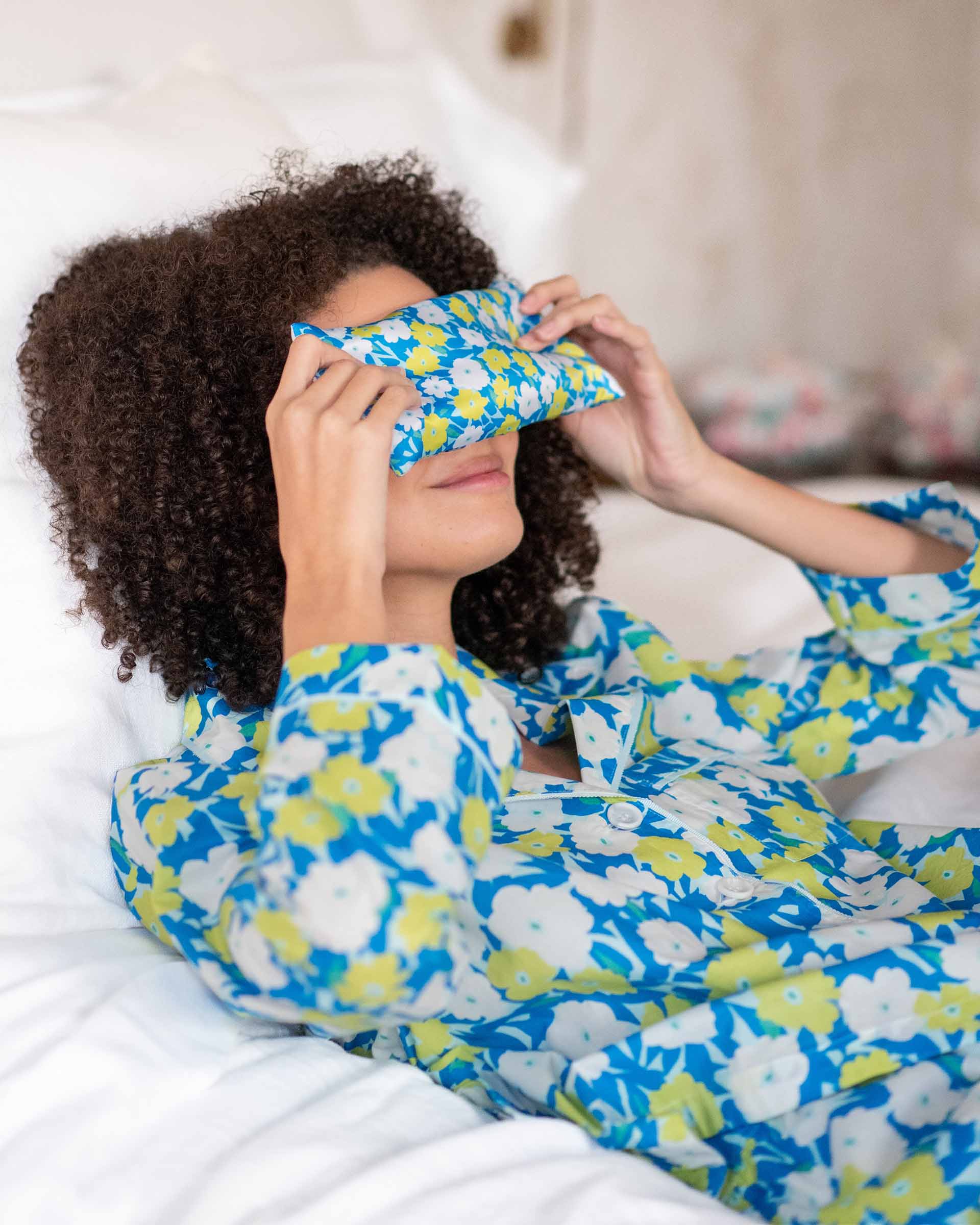 wearing laying on bed wearing over the cotton moon pjs in pop impatiens holding eye pillow on eyes