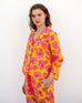 female wearing matching pajama set with pink poppy flower print standing in front of white wall
