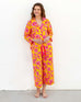 female wearing matching pajama set with pink poppy flower print leaning against white wall