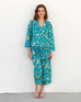 female wearing matching pajama set with ranunculus blue flower print leaning on white wall