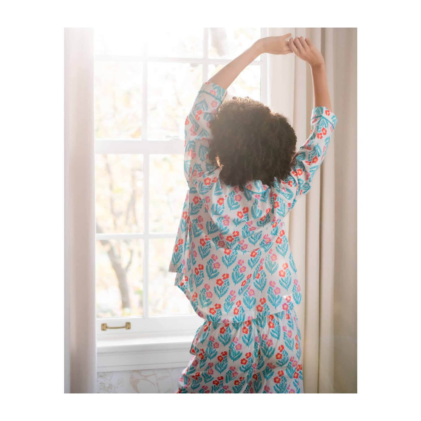 Women Stretching by Window In Flower Print Pajama Set