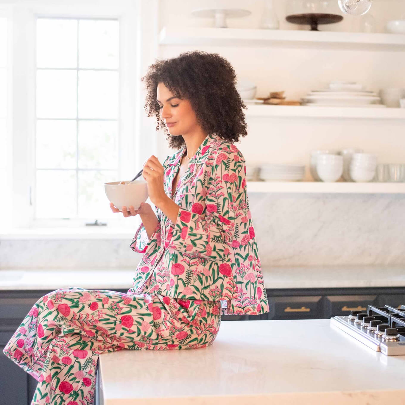 Woman in Kithcen Eating Cereal in Pink Peony Print Pajama Set