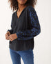 closeup of woman showcasing Mersea black v-neckline palermo blouse with embroidered sleeves and tassel ties