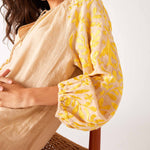 close up detail of woman wearing tan and yellow dress with embroidery