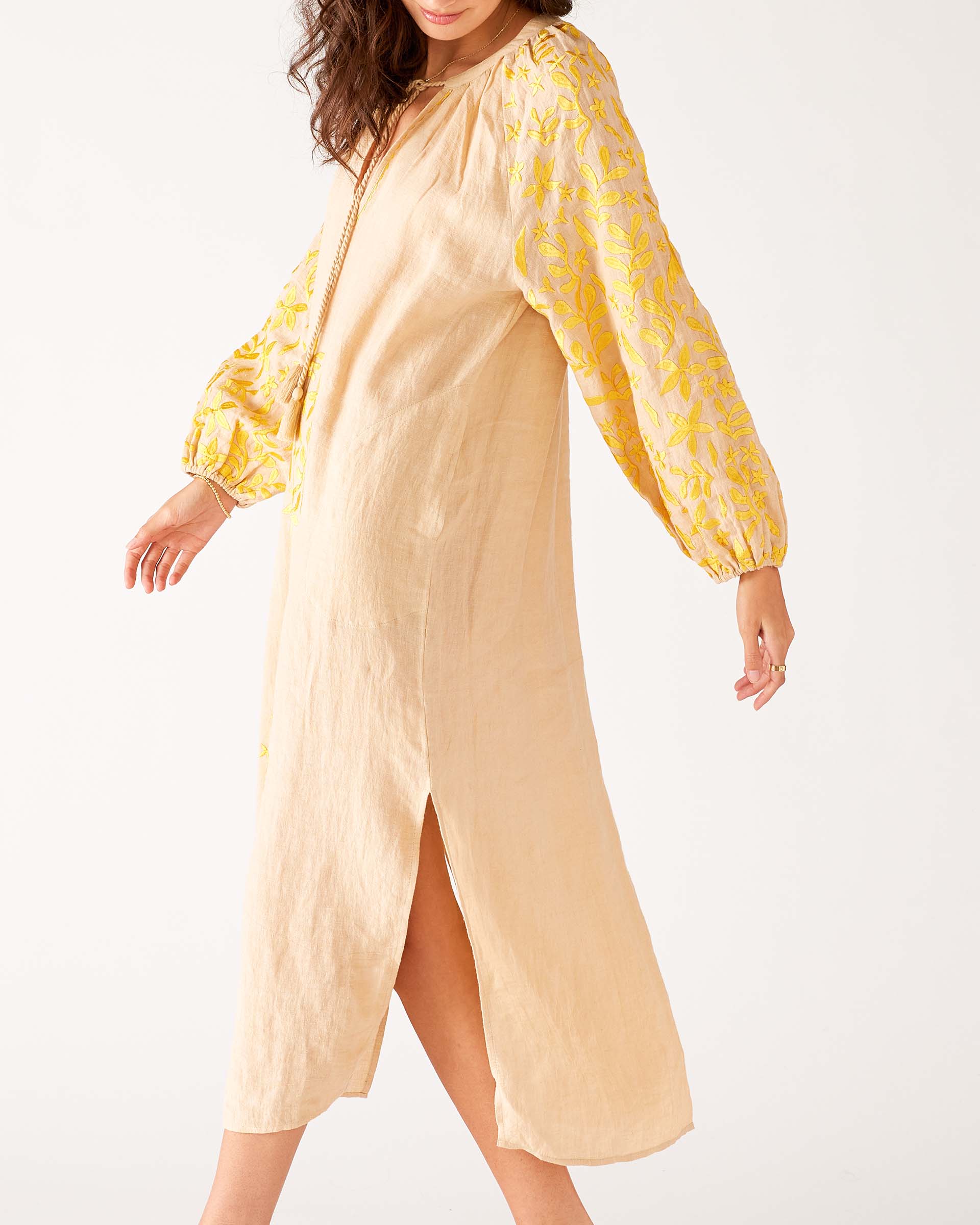 side detail of woman wearing tan and yellow maxi dress with embroidery