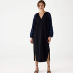 female wearing Mersea black embroidered maxi dress with V-neck and tassel ties on a white background