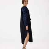 female standing sideways wearing Mersea black embroidered maxi dress with V-neck and tassel ties on a white background