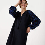 female wearing Mersea black embroidered maxi dress with tassel ties on a white background