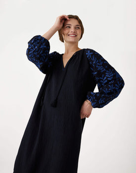 female wearing Mersea black embroidered maxi dress with tassel ties on a white background