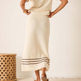 Person wearing a long cream skirt with a subtle pattern, standing against a plain background.